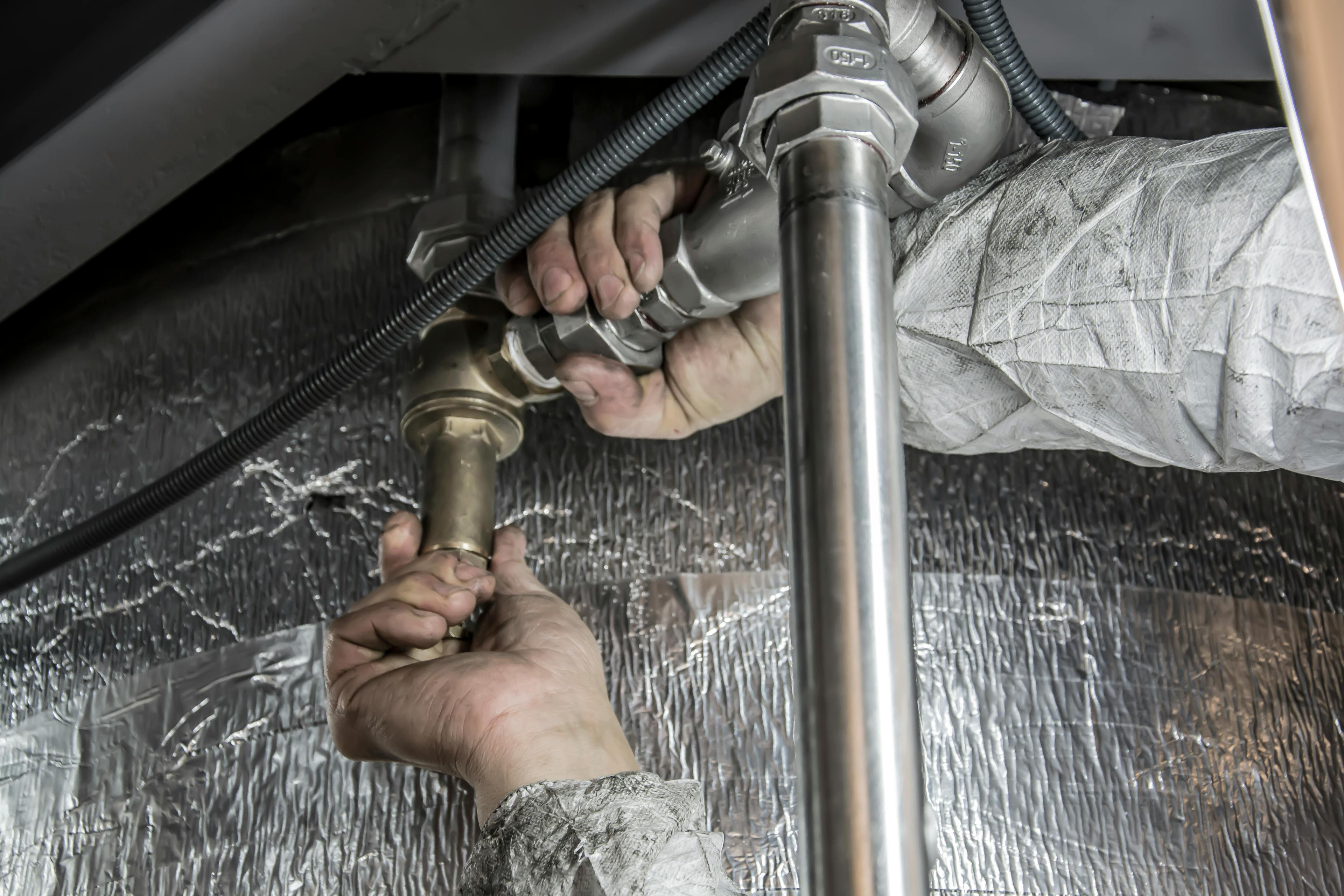 Technician repairing pipes under a water heater